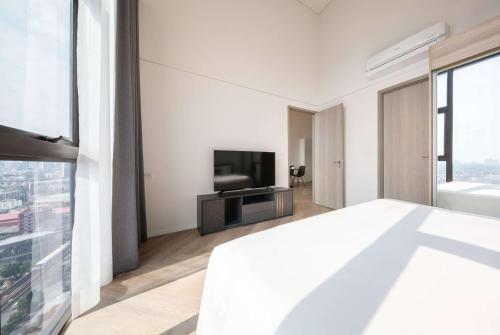 a white bedroom with a tv and a bed at Ramada By Wyndham Bangkok Sukhumvit 87 in Bangkok