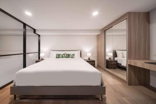 a bedroom with a large white bed and a mirror at Ramada By Wyndham Bangkok Sukhumvit 87 in Bangkok