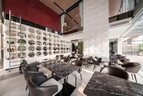 a restaurant with tables and chairs and a wall of plates at Ramada By Wyndham Bangkok Sukhumvit 87 in Bangkok