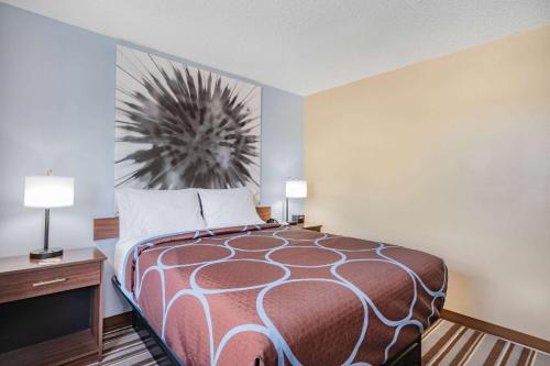 a bedroom with a bed and a desk with two lamps at Super 8 by Wyndham Joliet in Joliet