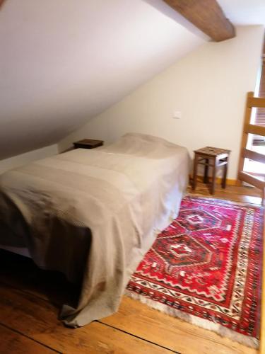 a bedroom with a bed and a rug on the floor at Maison charmante dans le village de Taintrux avec jardin in Taintrux