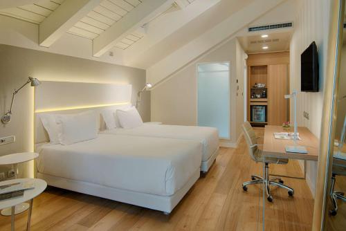 a bedroom with a large white bed and a desk at NH Collection Torino Santo Stefano in Turin