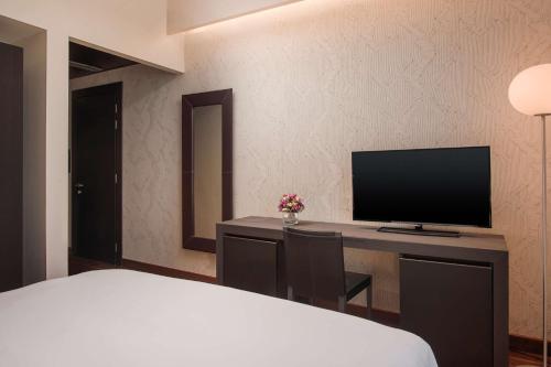 a bedroom with a bed and a desk with a television at NH Collection Torino Santo Stefano in Turin