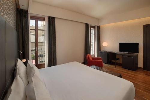 a hotel room with a bed and a desk at NH Collection Torino Santo Stefano in Turin