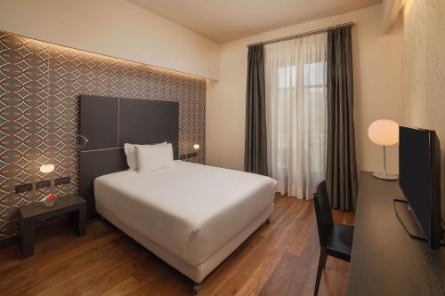 a hotel room with a white bed and a desk at NH Collection Torino Santo Stefano in Turin