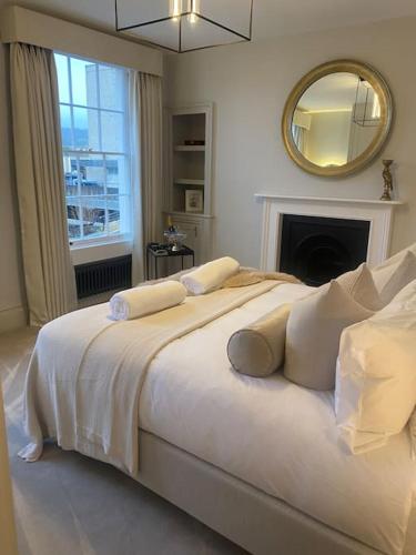 ein weißes Schlafzimmer mit einem großen Bett und einem Spiegel in der Unterkunft Luxury Georgian Apartment - 5 Minute Walk to Spa in Bath