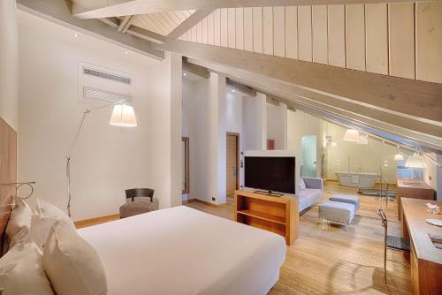 a bedroom with a large bed and a living room at NH Collection Torino Santo Stefano in Turin