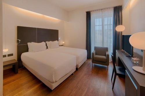 a hotel room with a large bed and a chair at NH Collection Torino Santo Stefano in Turin