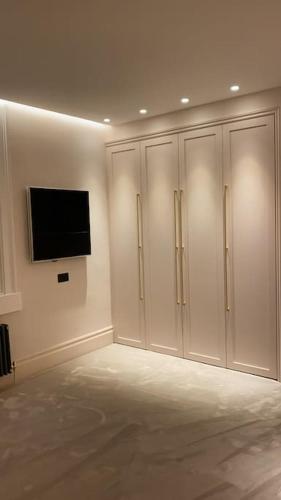 a room with white cabinets and a television on a wall at Luxury Georgian Apartment - 5 Minute Walk to Spa in Bath