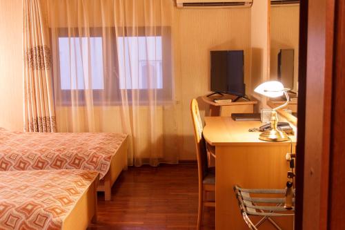 a hotel room with a desk and a bed and a television at Starye Bendery in Bender