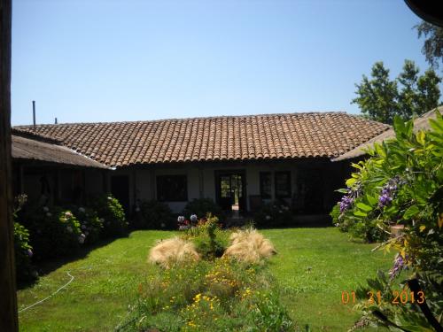 una casa con un patio con césped y flores en Casona Re-encuentro, en Yerbas Buenas