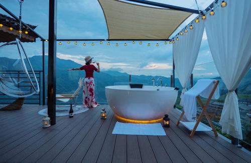 a woman standing next to a bath tub on a deck at Longji One Art Hotel in Longsheng