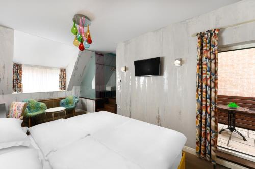 a bedroom with a white bed and a tv at Maison Bistro & Hotel in Budapest