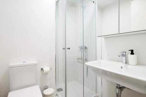 ein weißes Bad mit einer Dusche und einem Waschbecken in der Unterkunft Designer Studio Apartment 100m from the Beach in Las Palmas de Gran Canaria