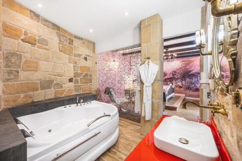 a bathroom with a large tub and a stone wall at Maison Bistro & Hotel in Budapest