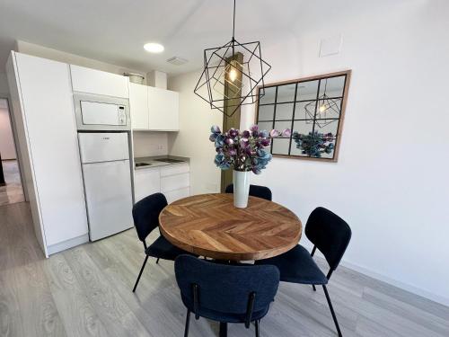 a kitchen with a table with chairs and a vase with flowers at Apartamentos Puerta Elvira Suites 3000 in Granada
