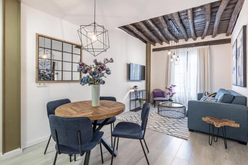 una sala de estar con una mesa con un jarrón de flores en Apartamentos Puerta Elvira Suites 3000 en Granada