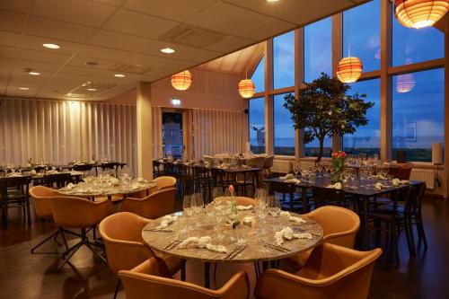 a dining room with tables and chairs and windows at Barsebäck Resort Hotell in Löddeköpinge