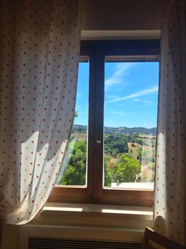 a window with a view of the countryside through it at Casale Terre Rosse Garden in Saturnia