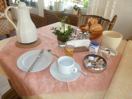 a table with two plates and a cup on it at Wein- und Gästehaus St. Aldegundishof in Sankt Aldegund