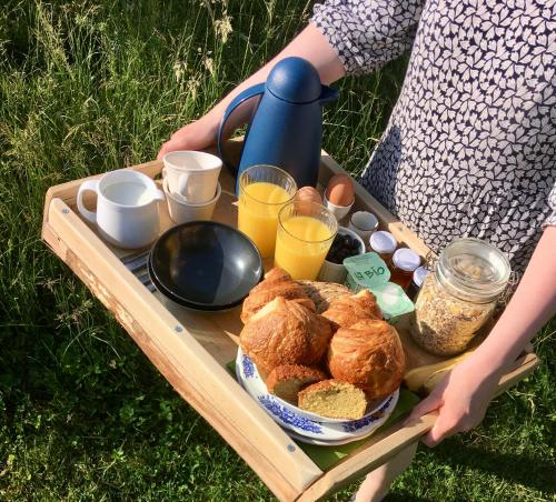 a woman holding a tray of bread and drinks at Camp Golstav - Romantic view over the hills. in Flobecq