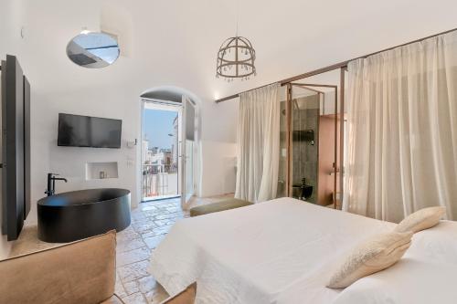 a bedroom with a tub and a bed and a tv at Arya Nobile Dimora in Carovigno