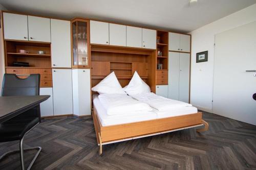 ヴェスターラントにあるHaus-am-Meer-App-30のベッドルーム1室(白いキャビネット付きのベッド1台、デスク付)