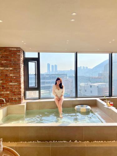 a woman sitting in a bath tub in a building at Poolvilla Gaon in Busan