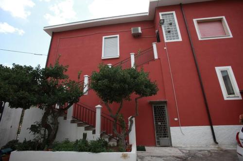 um edifício vermelho com escadas e árvores em frente em Villa Cecita Holiday em Sellia Marina