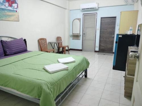 um quarto com uma cama verde com duas toalhas em DD Mansion em Ban Talat Rangsit
