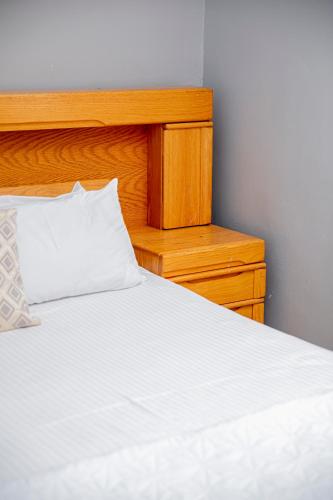 a white bed with a wooden headboard and a nightstand at The Afropolitan in Johannesburg