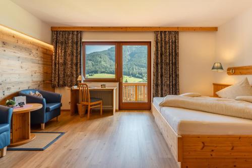 a hotel room with a bed and a large window at Wiesenhof, Hotel direkt am See in Weissensee