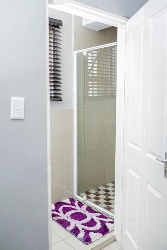 a bathroom with a shower with a purple rug at The Afropolitan in Johannesburg