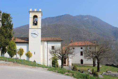 a building with a clock tower in front of a mountain at Locanda Genzianella in Gargnano