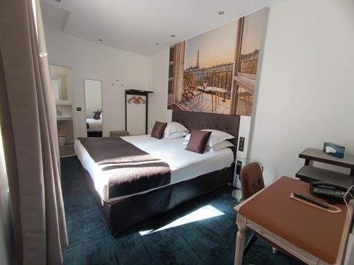 パリにあるホテル アイーダ マレのベッドとデスクが備わるホテルルームです。