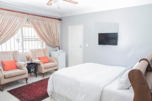a bedroom with a bed and two chairs and a tv at The Afropolitan in Johannesburg
