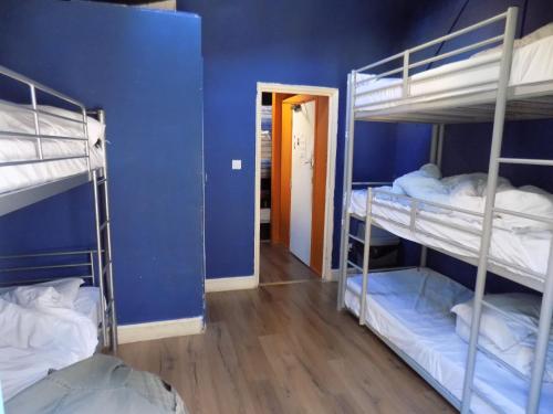 a room with three bunk beds and a blue wall at The Phoenix Hostel Paddington in London