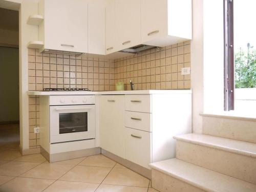 a kitchen with white cabinets and a stove top oven at Rimini in villa in Rimini