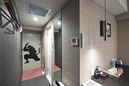 a bathroom with a door with a monkey stencil on the wall at Hotel Ninja Black in Kyoto