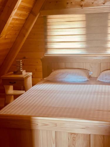 a bed in a wooden cabin with a window at Guest House LENA in Žabljak