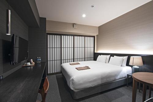 a hotel room with a large bed and a table at Hotel Ninja Black in Kyoto