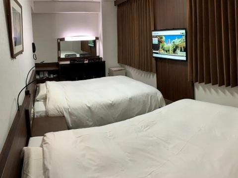 a room with two beds and a flat screen tv at Hotel Alpha-One Kitashinsaibashi in Osaka
