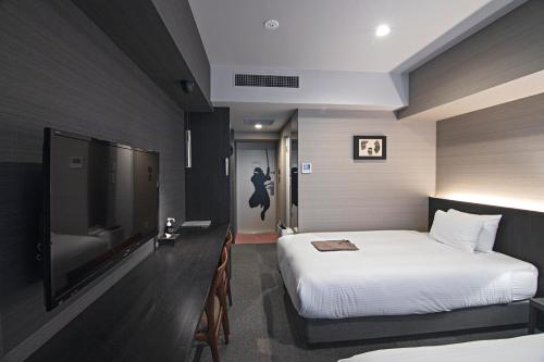 a hotel room with a bed and a flat screen tv at Hotel Ninja Black in Kyoto
