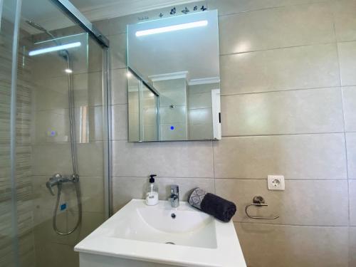 a bathroom with a sink and a shower and a mirror at On the Beach Holiday Home in Los Cristianos