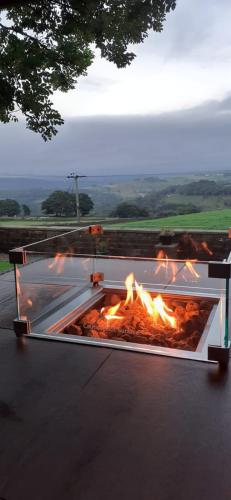 a fire pit on the ground with flames in it at The School House, Sowood, Halifax in Halifax