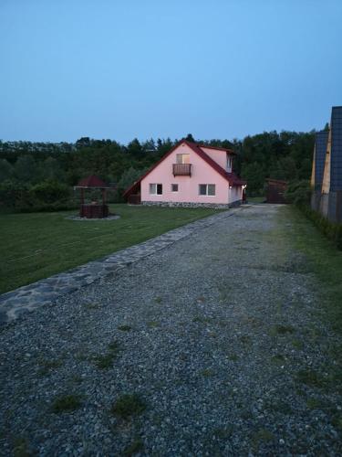 a gravel road with a white house and a gazebo at Family Mountain Cottage in Cârțișoara