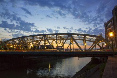 a train bridge over a river with a building at Tmark City Hotel Kanazawa in Kanazawa