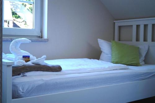 a white bed with a stuffed animal on top of it at REGIOHOTEL Aparthotel Wernigerode in Wernigerode