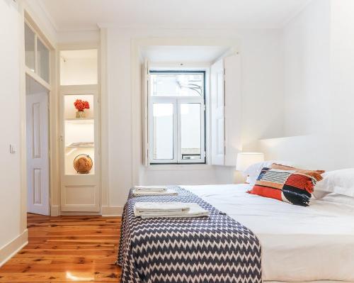 a white bedroom with a large bed and a window at Downtown Alfama & Me in Lisbon