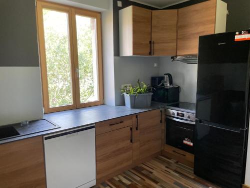 een keuken met houten kasten en een zwarte koelkast bij Chambre d’hôte proche gare et centre 1 in Besançon